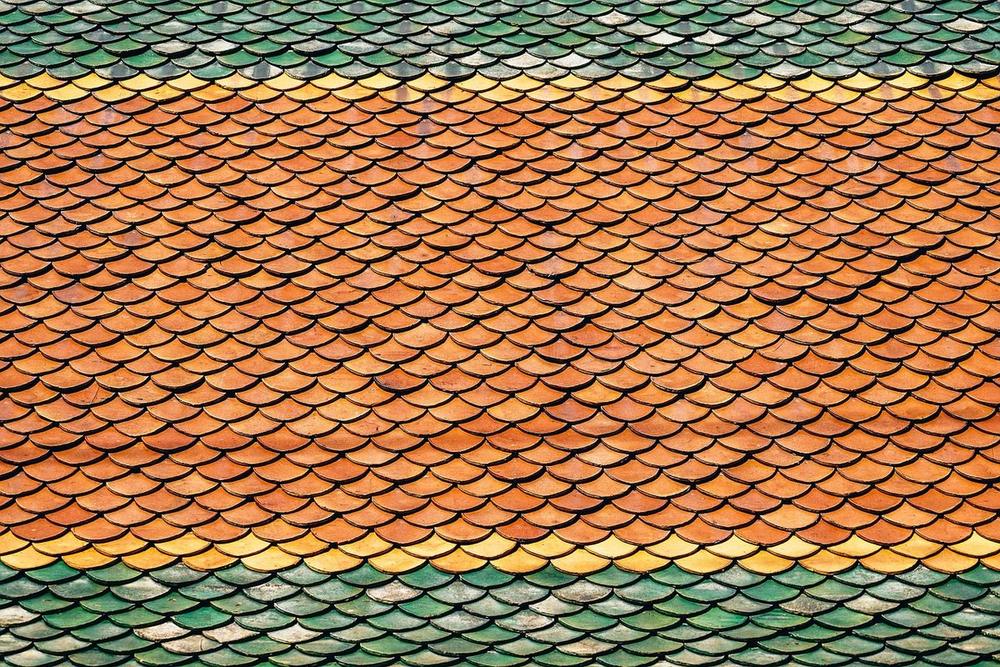 Close view of overlapping clay roof tiles in orange and green
