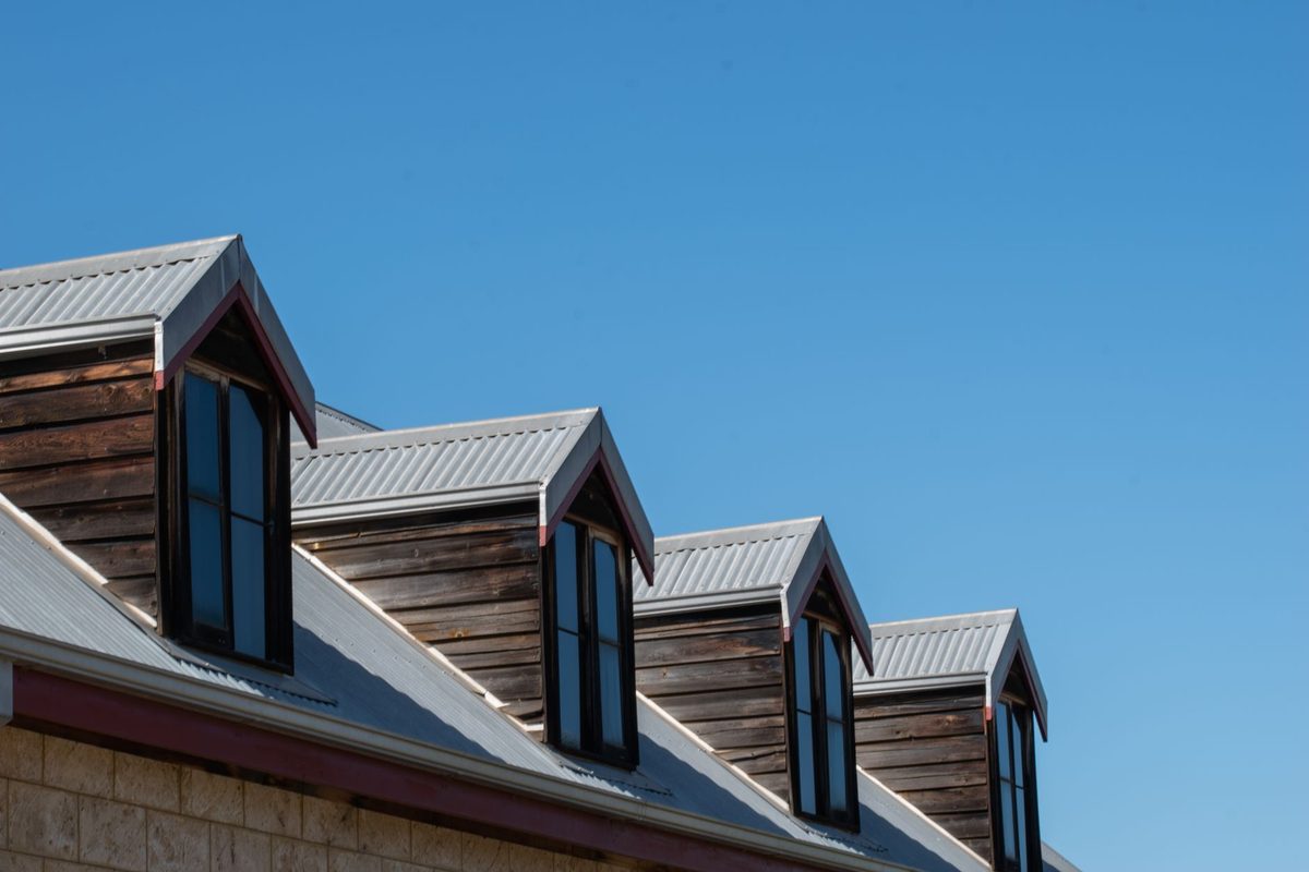 Row of timber dormers with metal roofs against a blue sky